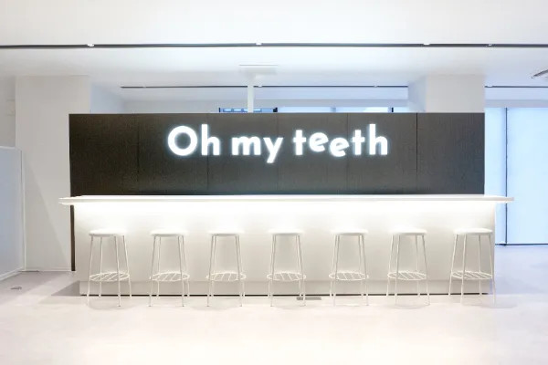 Oh my teeth名古屋店のエントランス:ネオンサインと白いカウンター