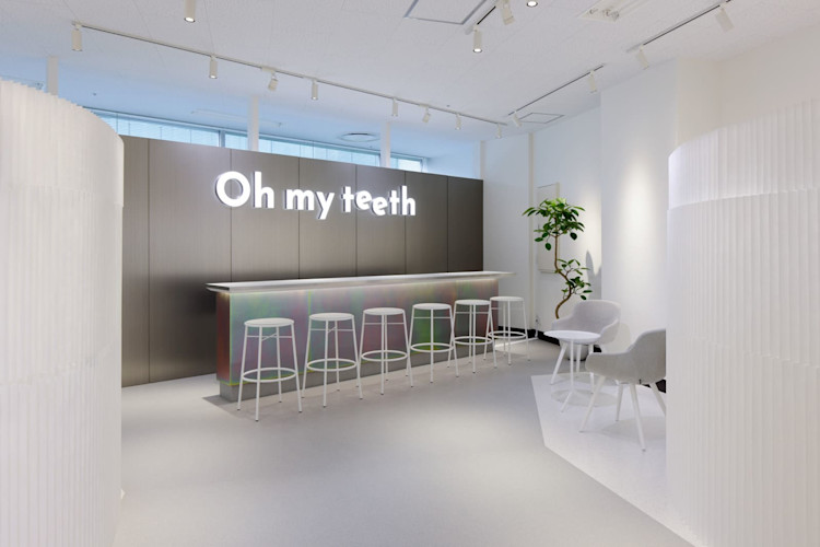 Oh my teeth広島店の待合エリア:「Oh my teeth」ネオンサインと白いスツール