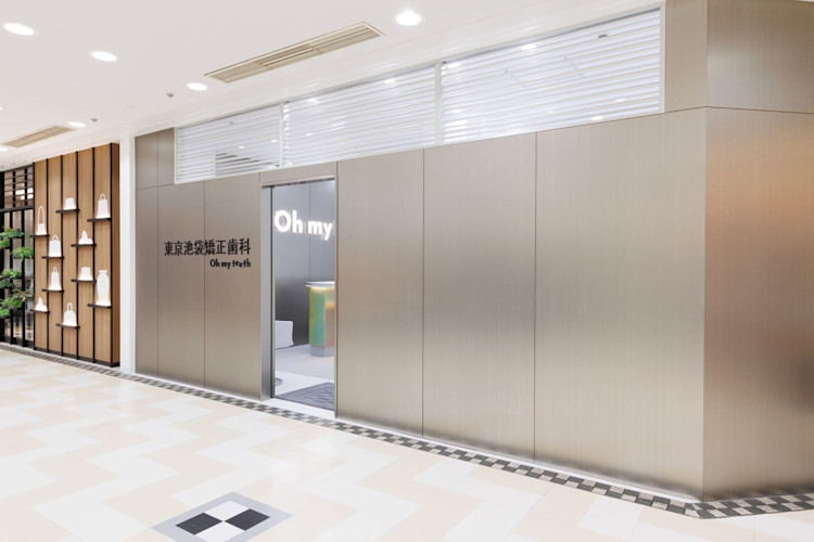 Oh my teeth池袋店のストアエントランス:ステンレスの入口と模様店のネオンサイン