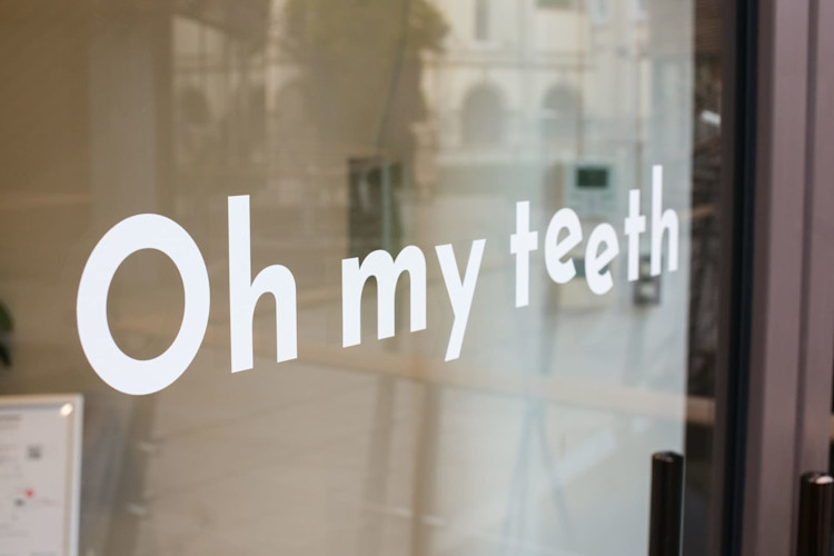 Oh my teeth表参道店のガラスドア:"Oh my teeth"のロゴ
